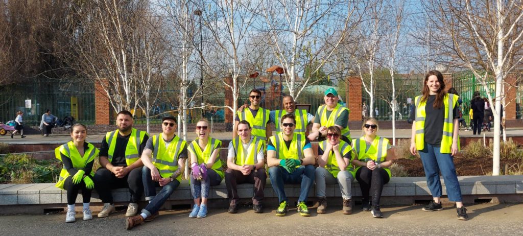 Group of people in high vis jackets by a garden